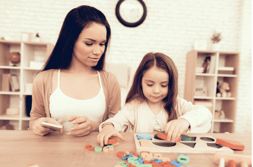 a woman and a young girl fit blocks inside a wooden board