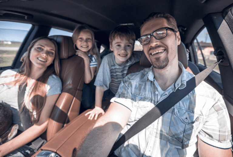 a smiling family traveling in a car