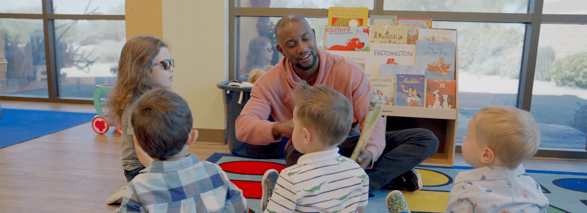 A man is surrounded by children engaged in teaching activity