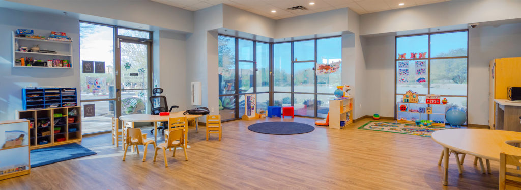 overview of a children's playroom filled with windows, tables, chairs, and toys